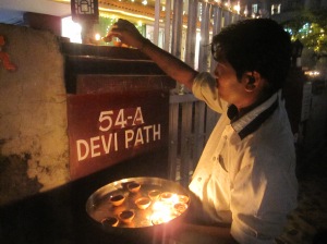 Moti putting up candles in front of our house as part of puja. 